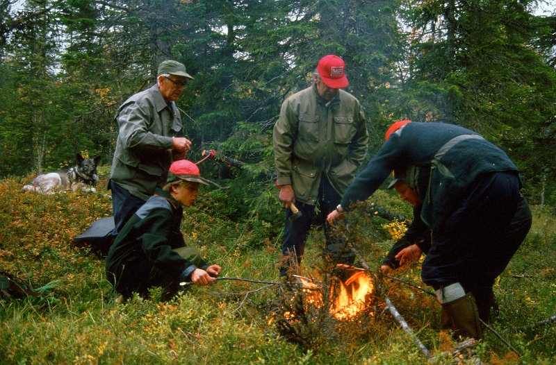 1987_03.jpg - Her er det kaffekoking og pølsegrilling i Furuskpogmyra ein seinere dag i jakta. Ungutten t.v er Gunnars sønn Jon Reidar. Vi ser også Jon, Gunnar Arvid og Trygve.